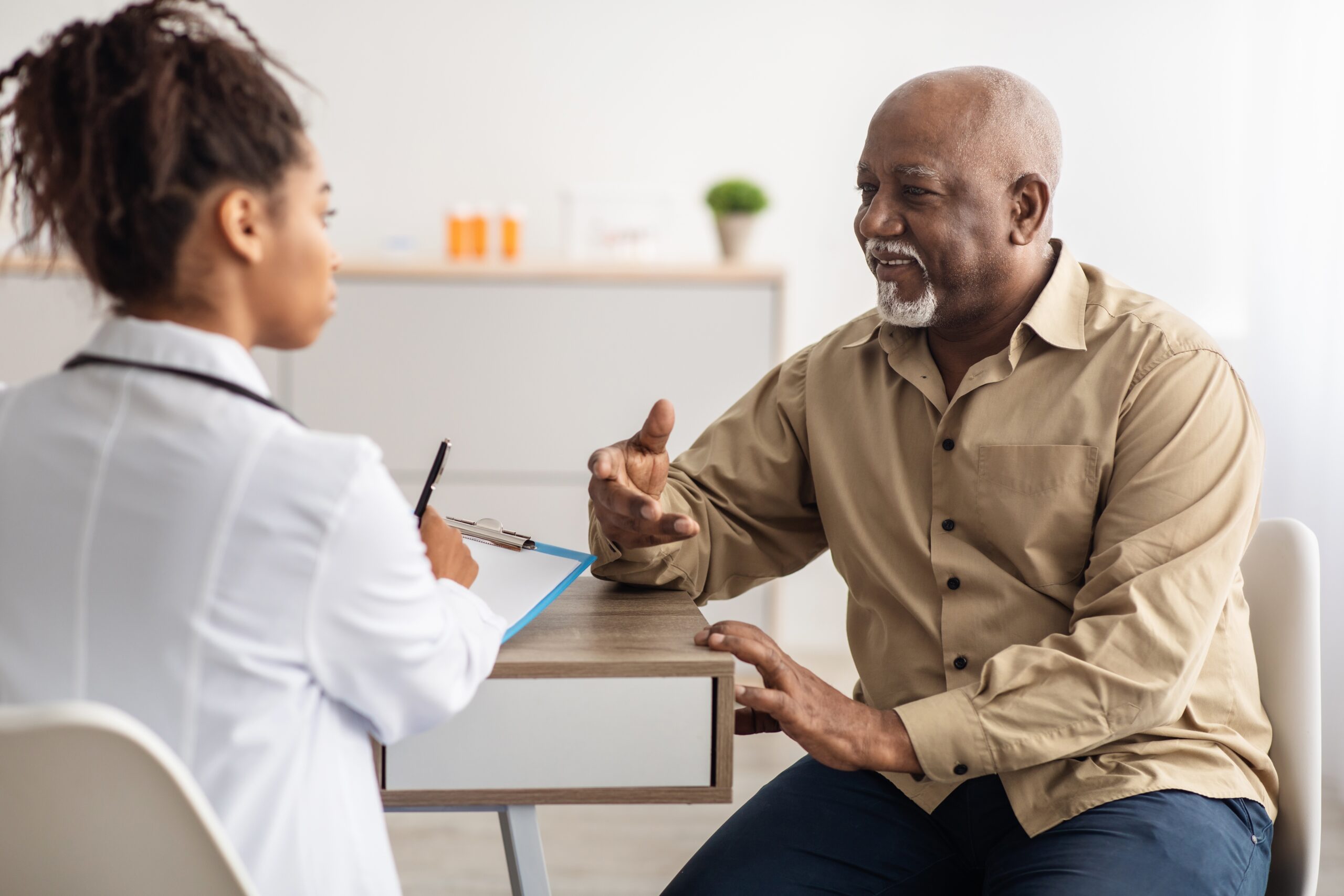 a man talks to a healthcare worker at a table in an office setting