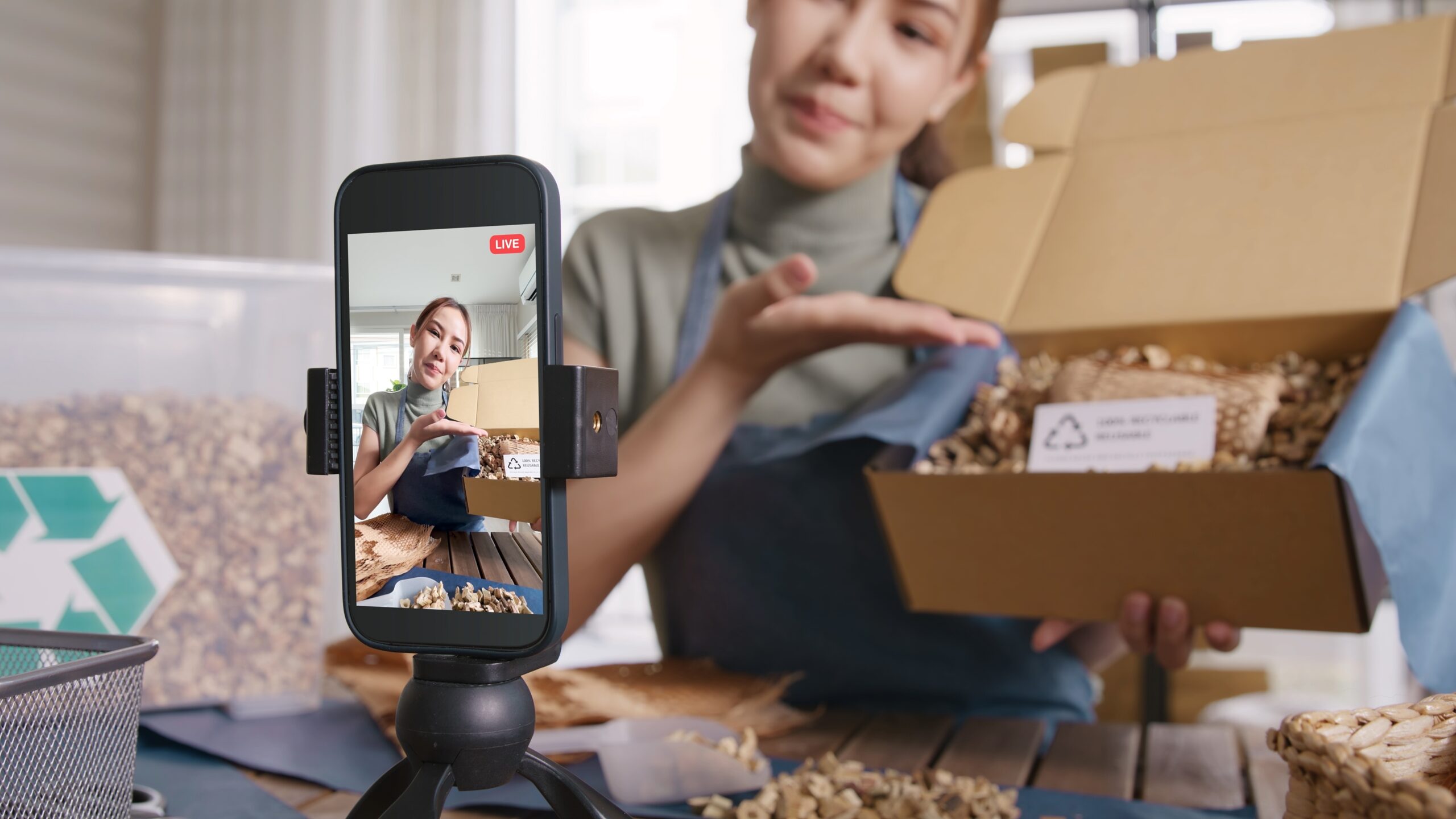 A woman is taking a video of her packaging product for marketing purposes.